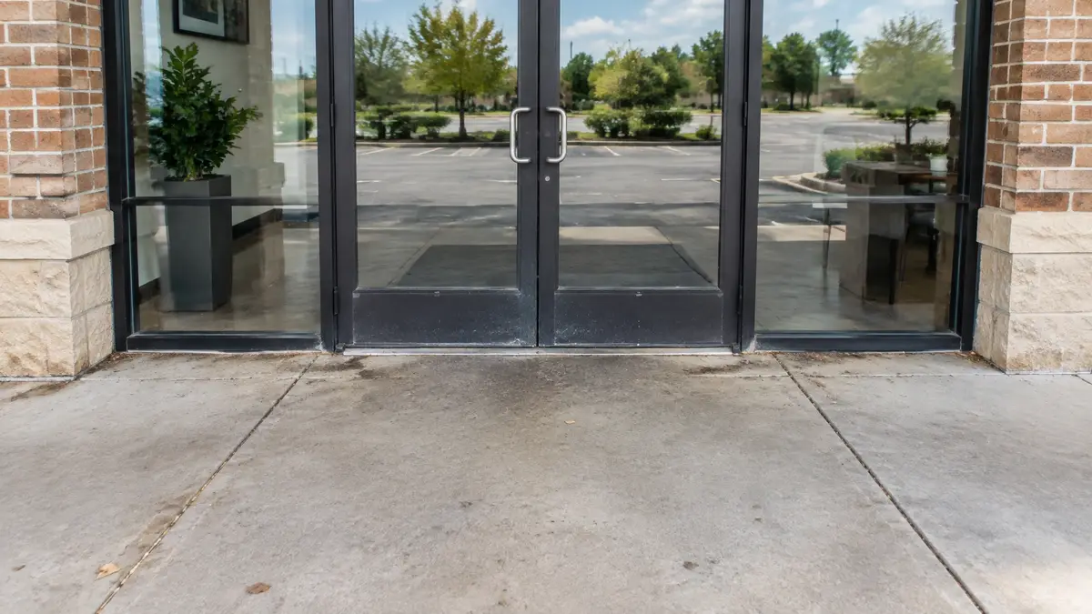 Commercial storefront entrance before exterior cleaning with a dusty threshold